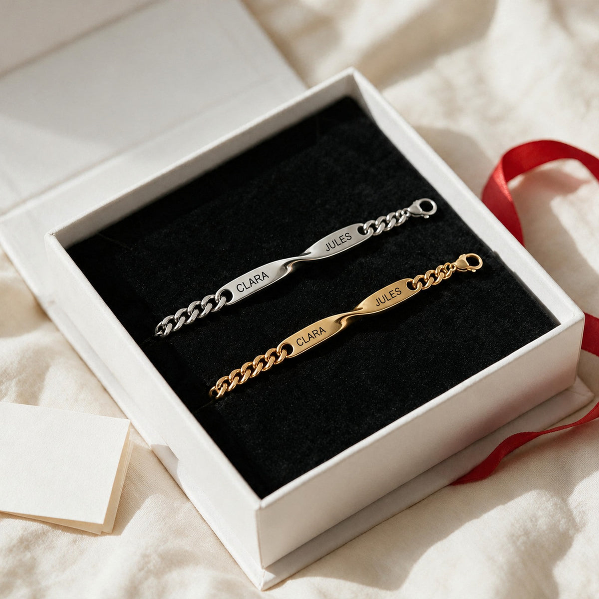 Coffret Liora ouvert sur un drap : bracelet argent et bracelet or gravés CLARA · JULES
